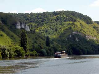 A barge carves its way between the wooded cliffs